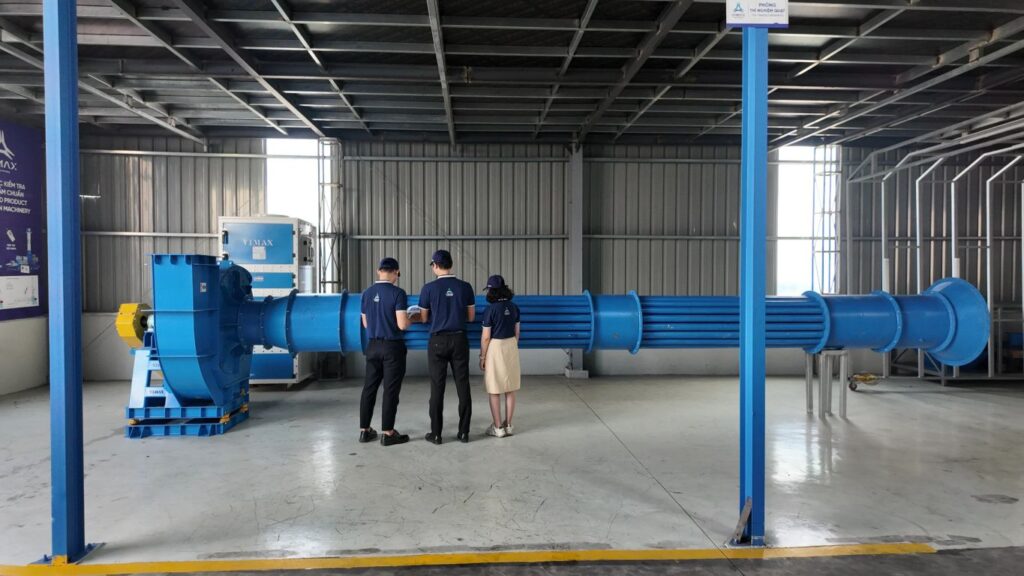 Visitors observing a large blue turbine in an industrial facility.
