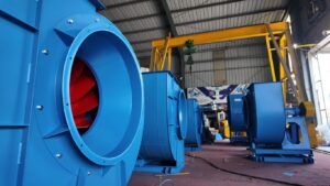 Industrial setting with large blue machinery and ventilation fans.