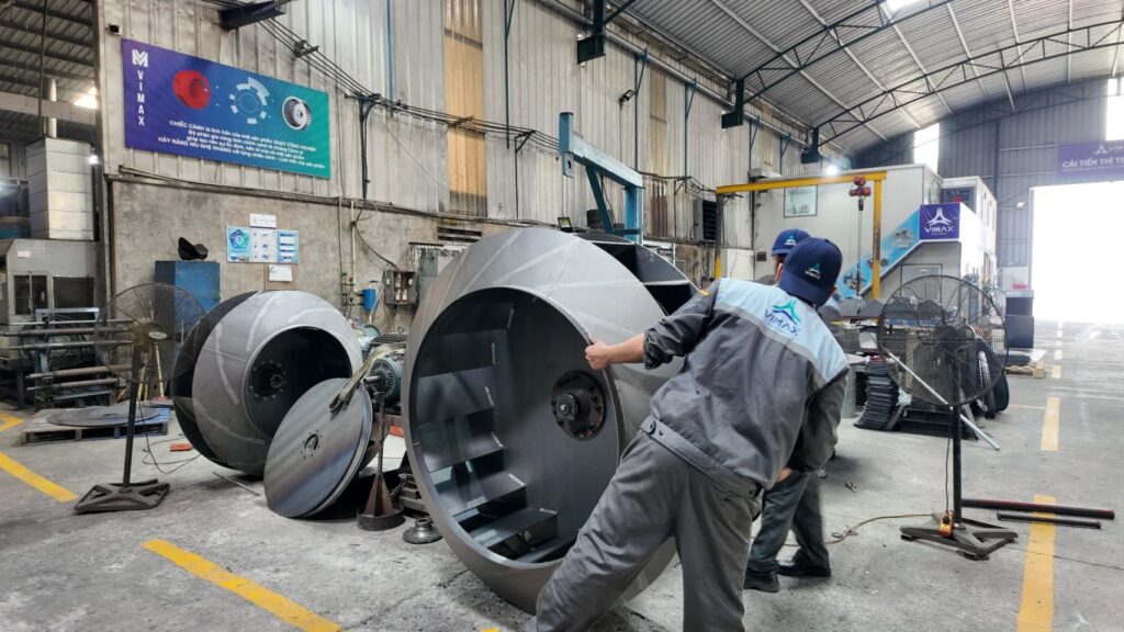 Workers handling large industrial equipment in a manufacturing facility.