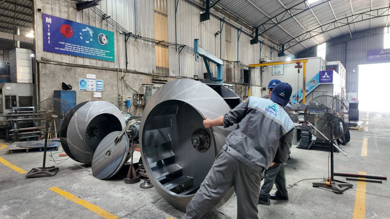 Workers handling large industrial equipment in a manufacturing facility.