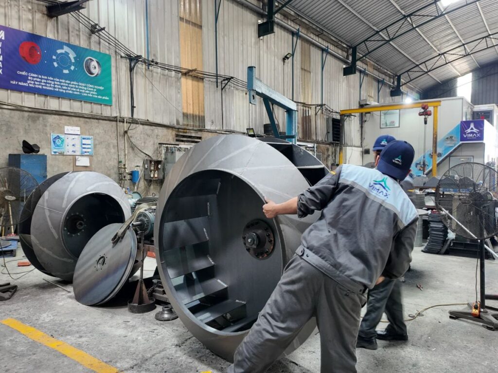 Workers handling large industrial equipment in a manufacturing facility.